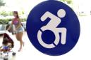 En esta imagen del miércoles 7 de octubre de 2015 se observa un letrero modernizado de discapacitados en una puerta de The Mall, en Milenia, Orlando, Florida. Los activistas quieren reemplazar el logo convencional de una figura estática en silla de ruedas con el nuevo logo, el cual enfatiza la capacidad y no la discapacidad. (Foto AP/Bill Sikes)
