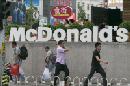 Transeúntes pasan por delante del logotipo de McDonalds en uno de sus establecimientos de comida rápida en Pekín (China). EFE