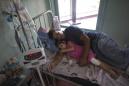 En esta imagen del 11 de agosto de 2016, Maykol Pacheco se acurruca con su hija Ashley en su cama de hospital, durante su estancia de dos meses en el Hospital Universitario de Caracas, en Venezuela. (AP Foto/Ariana Cubillos)
