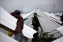 Un soldado observa a un hombre lavándose en un campo de desplazados de Cite Soleil, Puerto Príncipe (Haití). EFE/Archivo