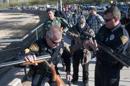 Una agente de policía de Tucson (Arizona) revisa una escopeta que le entrega un residente de esa ciudad a cambio de una tarjeta para comprar comida. EFE/Archivo