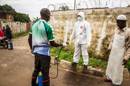 Un trabajador sanitario rocía con desinfectante a una persona que ayudó a cargar a un posible enfermo de ébola hasta una ambulancia en Freetown, Sierra Leona, el 24 de septiembre de 2014.(AP Foto/ Michael Duff)