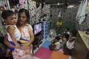 Lisa Villalon, embarazada de 8 meses, sostiene a su hijo más joven mientras sus otros cinco hijos se distraen con la televisión en Quezón, al este de Manila en Filipinas. EFE/Archivo