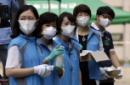 Trabajadores surcoreanos de un centro sanitario comunitario equipados con máscaras como medida de precaución contra el MERS, el síndrome respiratorio por coronavirus de Oriente Medio, esperan para tomarse la temperatura e higienizar sus manos en un ejercicio de simulación en Seúl, Corea de Sur, el 13 de junio de 2015. (Foto AP/Lee Jin-man)