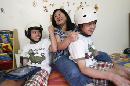 Arlene Aguirre,al centro, juega con sus hijos mellizos Clarence, izquierda, y Carl, de 12 años, en la casa de la familia en Scarsdale, Nueva York, el jueves, 31 de julio del 2014. La delicada separación hace 10 años de los dos siameses filipinos no fue perfecta, pero la madre de los niños dice que su mera supervivencia es razón suficiente para celebrar el aniversario.(Foto AP/Kathy Willens)