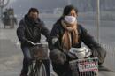 Una mujer china (dcha) se desplaza en bicicleta eléctrica y un hombre (izq) en bicicleta normal por Pekín. EFE