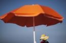 Esta foto tomada el martes 16 de junio del 2015 muesta a una mujer sentada debajo de una sombrilla mientras mira el mar, en la playa Folly Beach, en South Carolina. El protector solar podría no proteger contra tanto como uno cree. Aún después de que reguladores actualizaron sus estándares para etiquetar estos protectores en el 2012, pruebas indican que muchos ofrecen mucho menos protección de lo que anuncian. Si vas a estar a la intemperie, expertos recomiendan estar bajo la sombra y usar ropa que cubra tus brazos y piernas, y un sombrero ancho que proteja tu rostro, tus orejas y cuello. (Foto AP/David Goldman, Archivo)