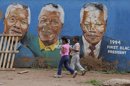 Dos niños pasan delante de una pintada con retratos de Nelson Mandela en Soweto, Johannesburgo (Sudáfrica). EFE/Archivo