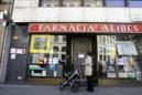 Una mujer contempla la fachada de una farmacia cerrada en el centro de Barcelona. EFE/Archivo