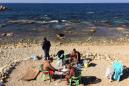 ARCHIVO - En esta fotografía de archivo del 9 de febrero de 2016, libaneses juegan cartas y fuman pipas de agua mientras se asolean en un inusualmente caliente clima en Corniche, Beirut, Líbano, en el mar Mediterráneo. (Foto AP/Hussein Malla)