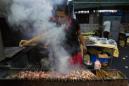 En esta imagen tomada el 26 de mayo de 2015, una trabajadora en un restaurante cocina pinchos de carne en Beijing. Más de un año después de que el primer ministro chino, Li Keqiang, declarase la guerra a la contaminación en todo el país, la gran batalla de Beijing contra el smog está transformando esta megalópolis de 20 millones de personas en formas grandes y pequeñas. .(AP Foto/Ng Han Guan)