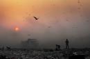 En esta imagen de archivo del 17 de octubre de 2014, una densa capa de humo ensombrece el atardecer mientras jóvenes chatarreros buscan materiales reutilizables en un vertedero de Nueva Delhi, India. La contaminación en el aire en India está reduciendo una media de tres años las vidas de 660 millones de personas, según un nuevo estudio publicado el sábado, y casi todos los 1.200 millones de habitantes del país respiran en entornos con niveles dañinos de polución. (AP Foto/Altaf Qadri, Archivo)