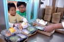 Dos estudiantes retiran su ración de comida en el comedor de una escuela primaria. EFE/Archivo