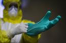 Un hombre se pone guantes especiales durante una demostración de un traje preventivo. EFE/Archivo