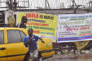 Un par de personas pasan junto a letreros que advierten de los riesgos del virus del ébola, en la ciudad de Monrovia, Liberia, el domingo 17 de agosto de 2014. (Foto AP/Abbas Dulleh)