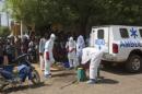 Health workers put on protective gear outside a mosque before disinfecting it, in Bamako