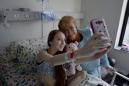 En imagen dada a conocer por la oficina de prensa del gobierno chileno, la presidenta Michelle Bachelet posa para una fotografía con Valentina Maureira, la adolescente que sufre fibrosis quística, en un hospital en Santiago, Chile, el sábado 28 de febrero de 2015. La presidenta visitó el sábado a Maureira, de 14 años, que sufre la enfermedad incurable y que días atrás le pidió a Bachelet permiso para morir por eutanasia, en un vídeo que subió a YouTube. (Foto AP/oficina de prensa de la presidencia de Chile)