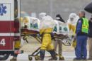 Trabajadores sanitarios con trajes de protección transportan al doctor Martin Salia, un cirujano que trabajaba en Sierra Leona diagnosticado de ébola, desde un jet que le llevó de Sierra Leona a una ambulancia que le llevaría al Centro Médico de Nebraska en Omaha, Nebraska, Estados Unidos. El doctor Salia es el tercer paciente de ébola que atiende el hospital y el décimo atendido en Estados Unidos. (AP Foto/Nati Harnik)