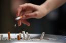 Una persona tira la ceniza junto a colillas de cigarrillo en un cenicero. EFE/Archivo