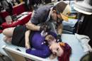 Un hombre realiza un tatuaje a una chica durante una feria. EFE/Archivo