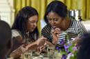 En esta imagen del 14 de octubre del 2014, la primera dama Michelle Obama y una estudiante almuerzan en la Casa Blanca en Washington. Los republicanos en la Cámara de Representantes buscan interrumpir la aplicación de las normas de alimentos saludables en las escuelas que promovió la primera dama. (AP Foto/Susan Walsh, Archivo)
