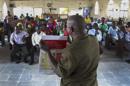 Un trabajador liberiano de UNICEF lee un cartel con información sobre el virus del ébola a varios ciudadanos durante una campaña de prevención del virus en una iglesia de la localidad de Newkru, en Monrovia (Liberia) ayer 22 de junio de 2014. EFE